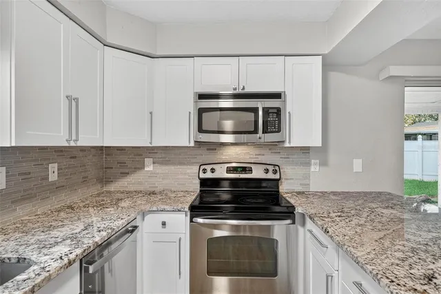 a kitchen with granite countertop a stove top oven microwave and cabinets
