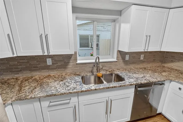 a kitchen with granite countertop a sink a stove and cabinets