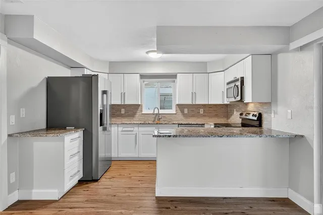a kitchen with stainless steel appliances granite countertop a refrigerator and a stove top oven