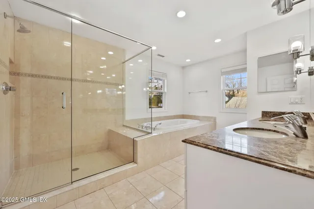 a bathroom with a granite countertop sink a mirror and shower