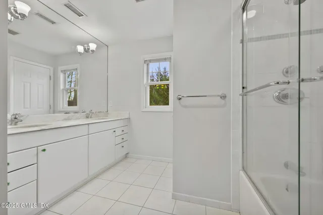 a spacious bathroom with a granite countertop sink a mirror and a shower