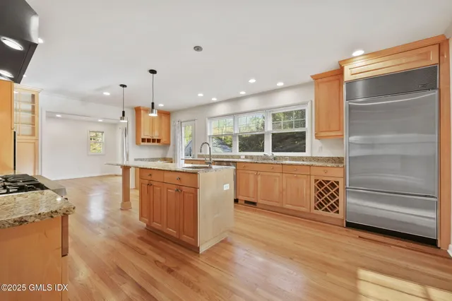 a kitchen with stainless steel appliances kitchen island granite countertop a stove a sink and a refrigerator