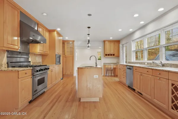a large kitchen with stainless steel appliances granite countertop a stove a sink dishwasher and a refrigerator