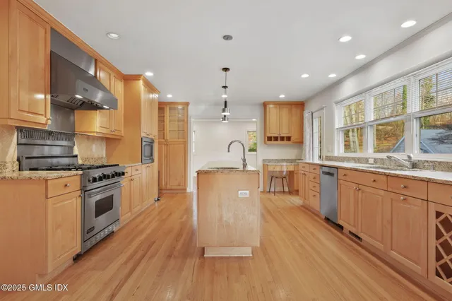 a large kitchen with stainless steel appliances granite countertop a stove a sink dishwasher and a refrigerator