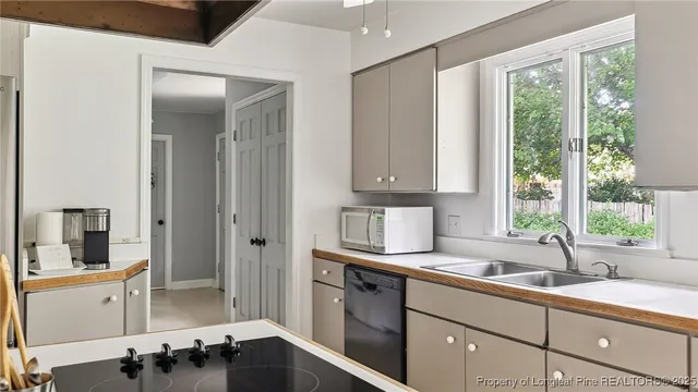 a kitchen with a stove a sink a window and cabinets