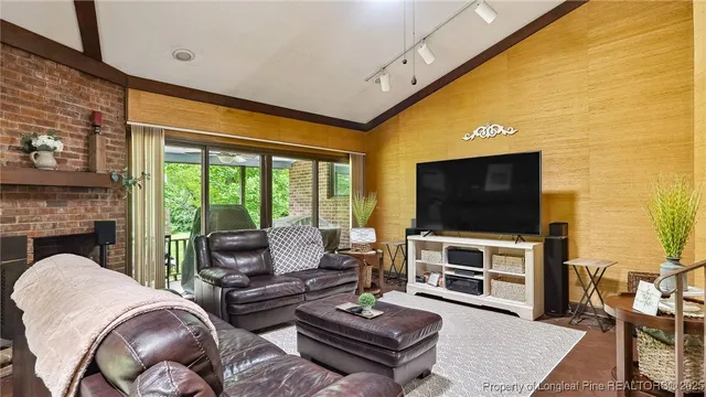 a living room with furniture a flat screen tv and a floor to ceiling window