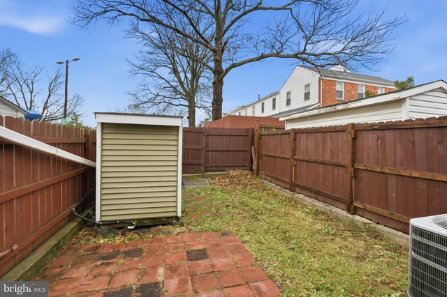 a view of a white house with a large tree and wooden fence