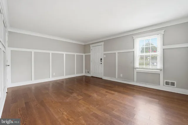a view of an empty room with wooden floor and windows