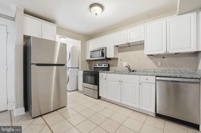 a kitchen with granite countertop a refrigerator sink and cabinets