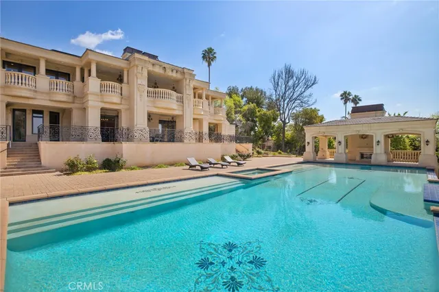 a spacious bedroom with a bed a chandelier and large windows
