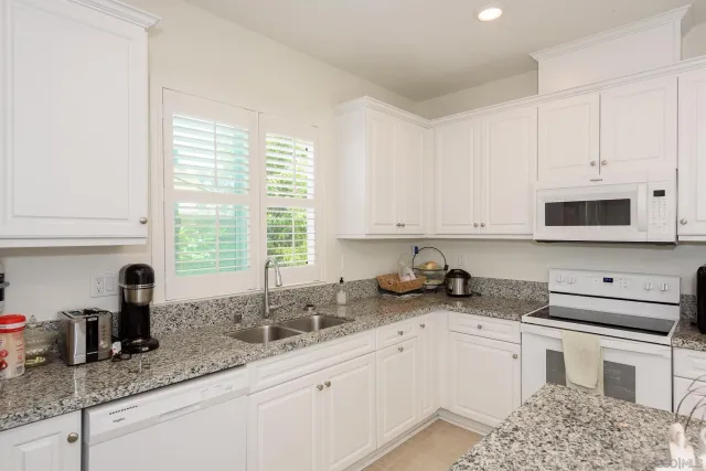 a kitchen with stainless steel appliances granite countertop a sink a stove and cabinets