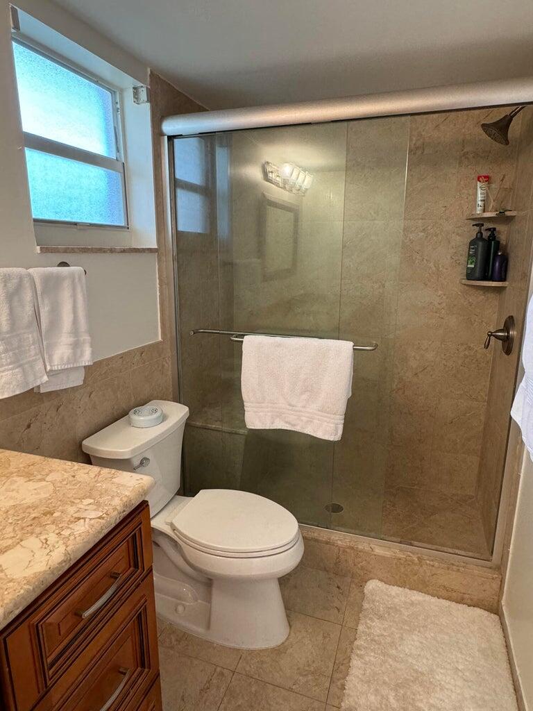 650 Snug Harbor Drive, Unit G110 Boynton Beach, FL 33435 - Photo 15 of 34 a bathroom with a granite countertop toilet sink and mirror