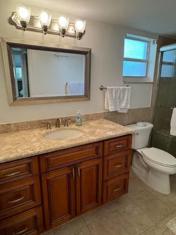 a bathroom with a granite countertop toilet sink and a mirror