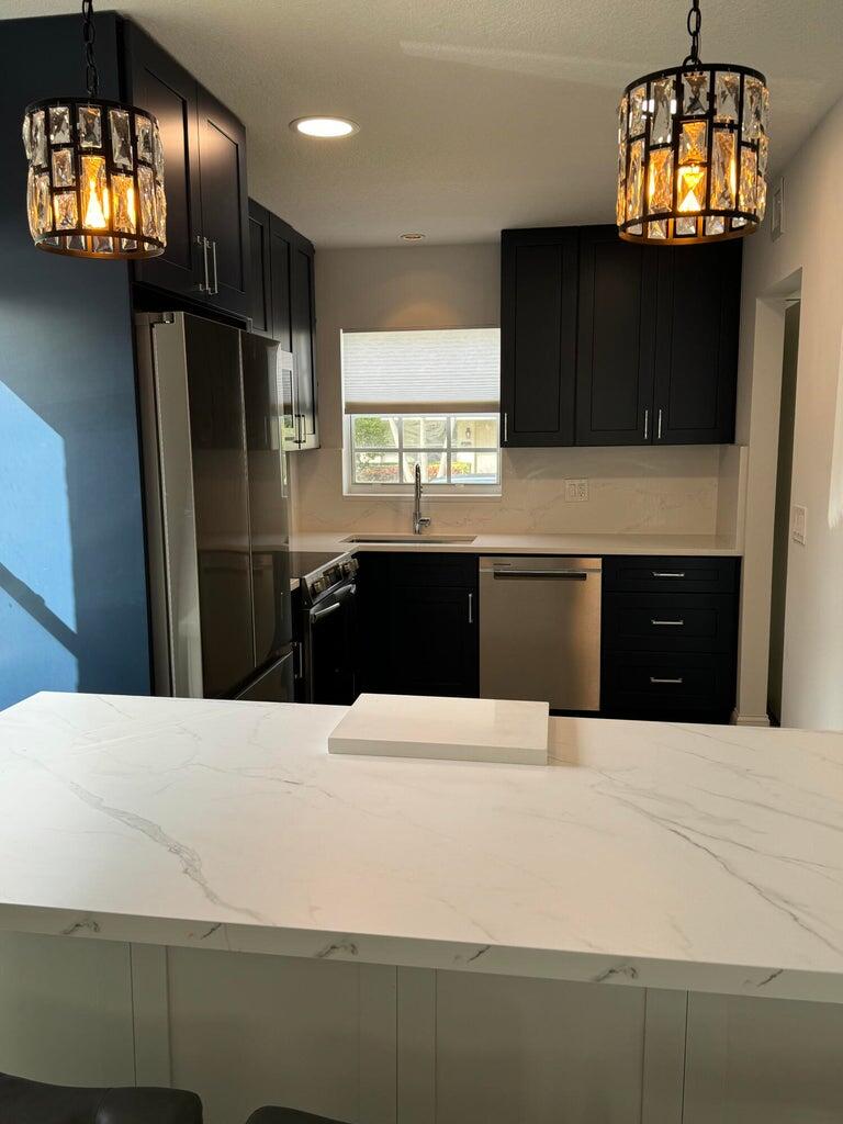 650 Snug Harbor Drive, Unit G110 Boynton Beach, FL 33435 - Photo 4 of 34 a kitchen with stainless steel appliances kitchen island granite countertop a refrigerator and a stove top oven