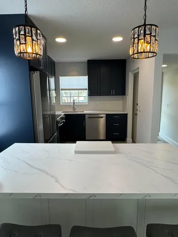 a kitchen with kitchen island a refrigerator wooden floor and a sink