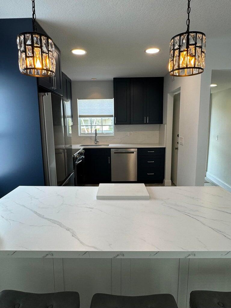 650 Snug Harbor Drive, Unit G110 Boynton Beach, FL 33435 - Photo 5 of 34 a kitchen with kitchen island a refrigerator wooden floor and a sink