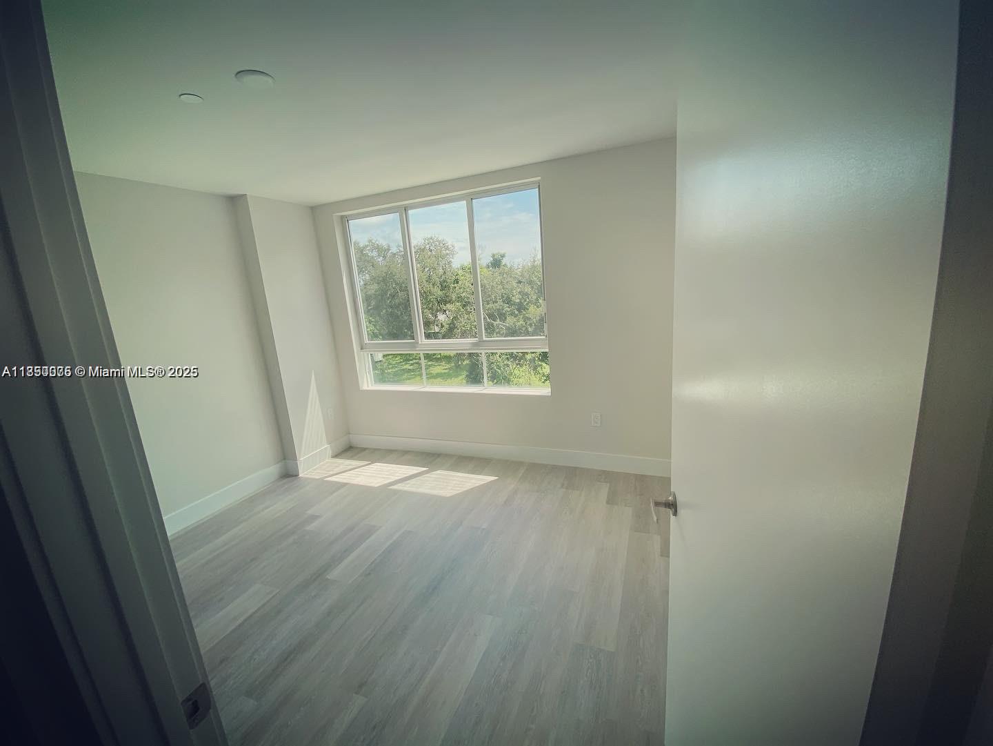 2505 Northeast 193rd Street, Unit 4204 Aventura, FL 33180 - Photo 5 of 18 an empty room with wooden floor and windows