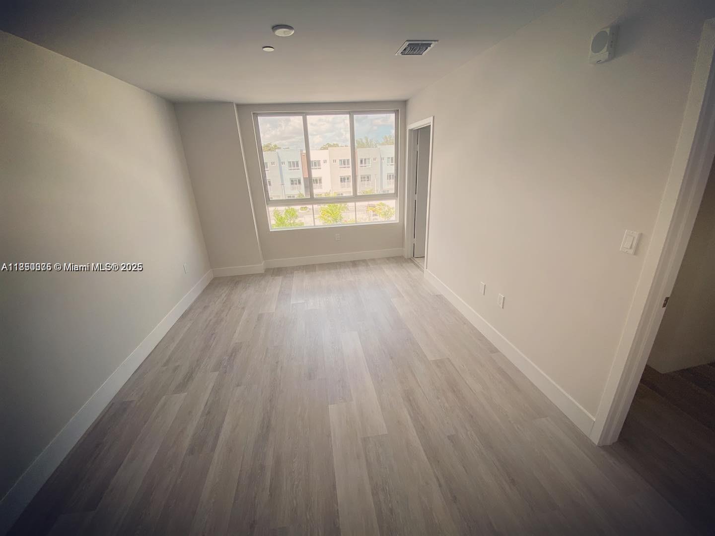 2505 Northeast 193rd Street, Unit 4204 Aventura, FL 33180 - Photo 10 of 18 an empty room with wooden floor and windows