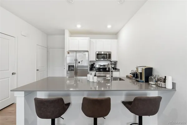 a kitchen with stainless steel appliances a sink a stove a microwave a dining table and chairs