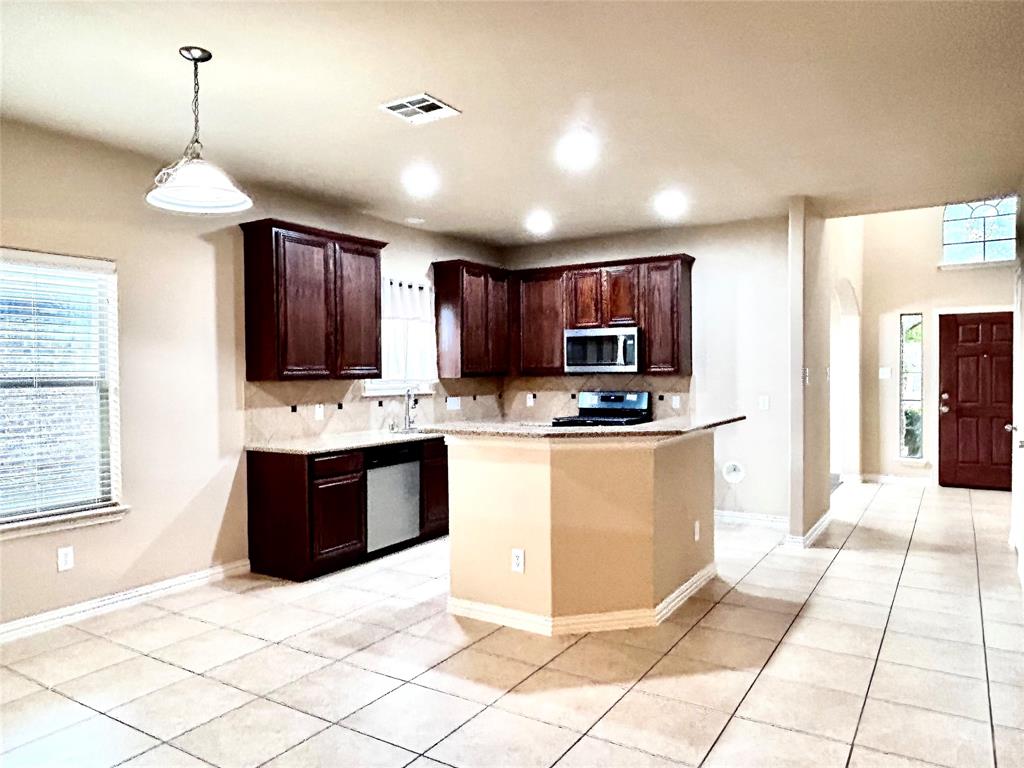 5112 Promised Land Drive McKinney, TX 75071 - Photo 22 of 30 a large kitchen with kitchen island granite countertop a refrigerator a stove a sink and a wooden cabinets