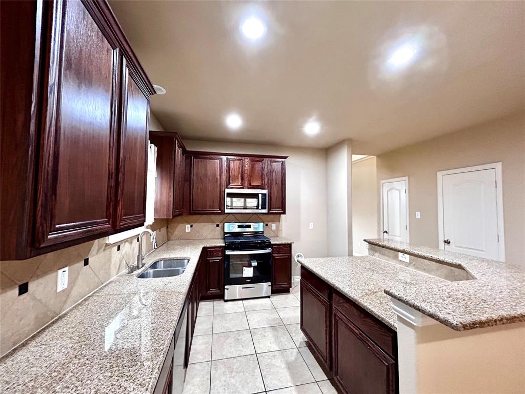 5112 Promised Land Drive McKinney, TX 75071 - Photo 7 of 30 a kitchen with stainless steel appliances granite countertop a sink stove and cabinets