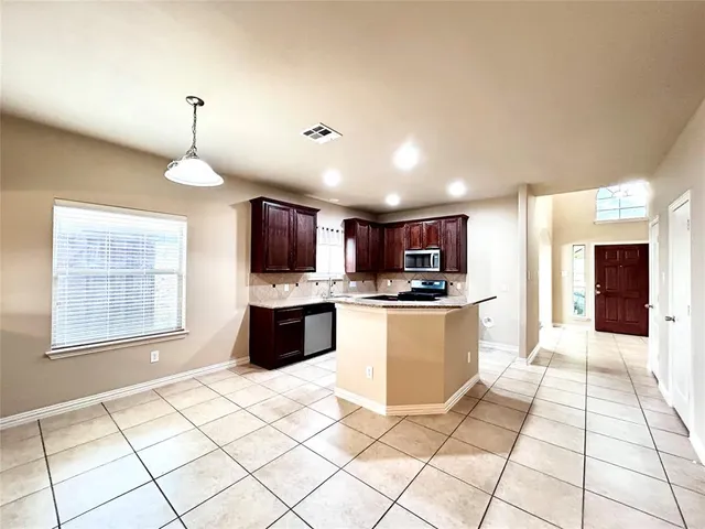 a large kitchen with kitchen island granite countertop a stove a sink dishwasher and a fireplace with wooden floor