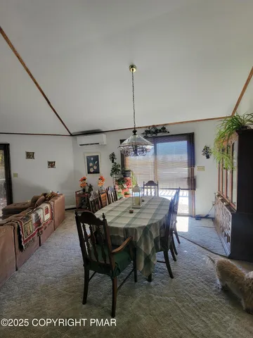 a view of a dining room and livingroom with furniture wooden floor a rug a painting and a chandelier