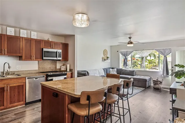 a open kitchen with stainless steel appliances granite countertop a stove a sink dishwasher a dining table and chairs with wooden floor