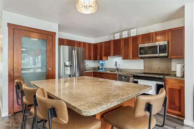 a kitchen with stainless steel appliances granite countertop a stove a refrigerator a kitchen island a table and chairs in it