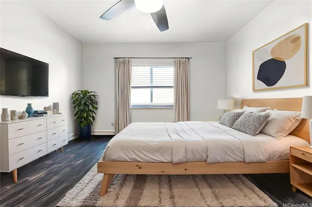 a bedroom with a large bed and a flat tv screen on dresser