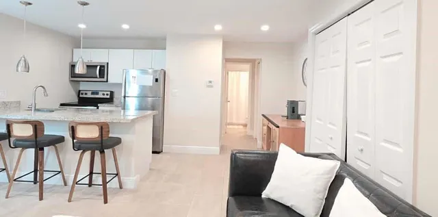 a kitchen with stainless steel appliances kitchen island granite countertop a refrigerator a stove and white cabinets