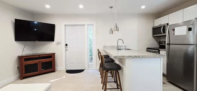 a living room with furniture a flat screen tv and kitchen view