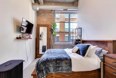 a bedroom with a bed a flat screen tv and a exposed radiator