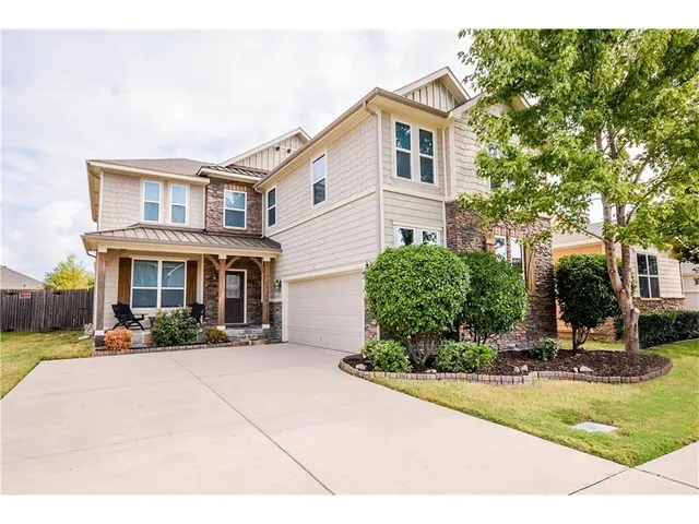 a view of a white house with large windows and a yard with plants