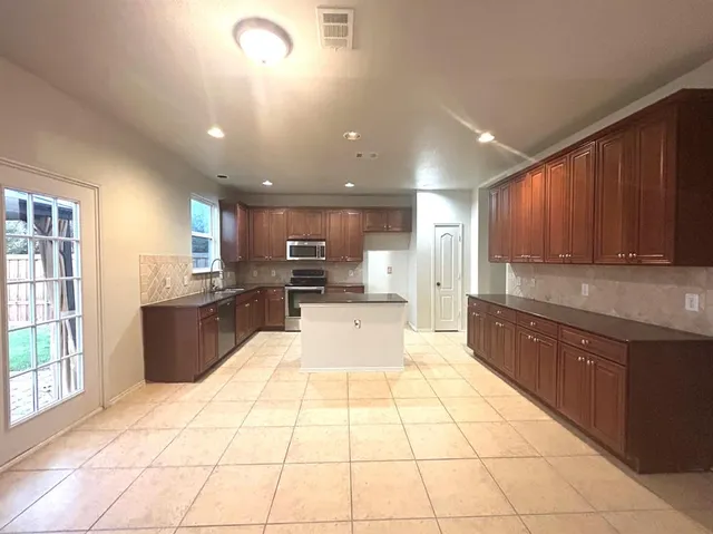 a large kitchen with kitchen island a large counter space a sink and appliances