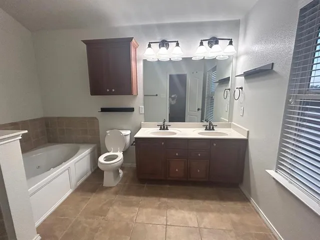a bathroom with a tub a sink and a large mirror