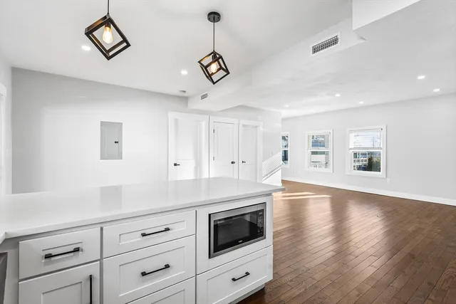 a kitchen with stainless steel appliances white cabinets and a wooden floor