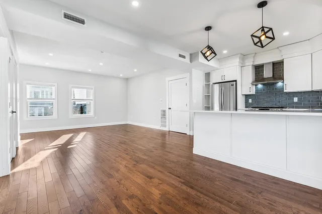 a view of large kitchen with granite countertop a stove and a wooden floors