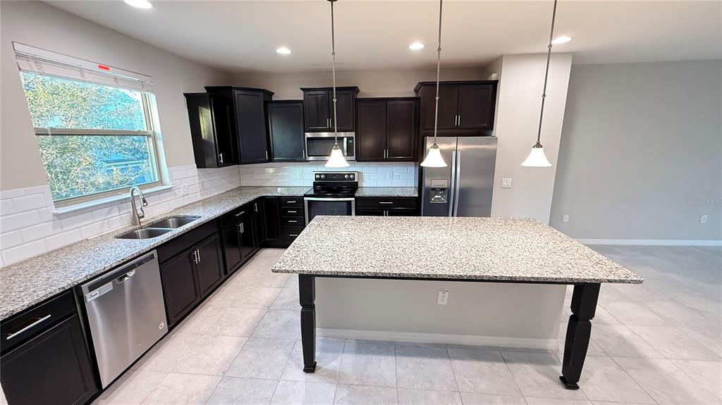 588 Piazza Point Oviedo, FL 32765 - Photo 13 of 66 a large kitchen with a center island wooden floor stainless steel appliances and window