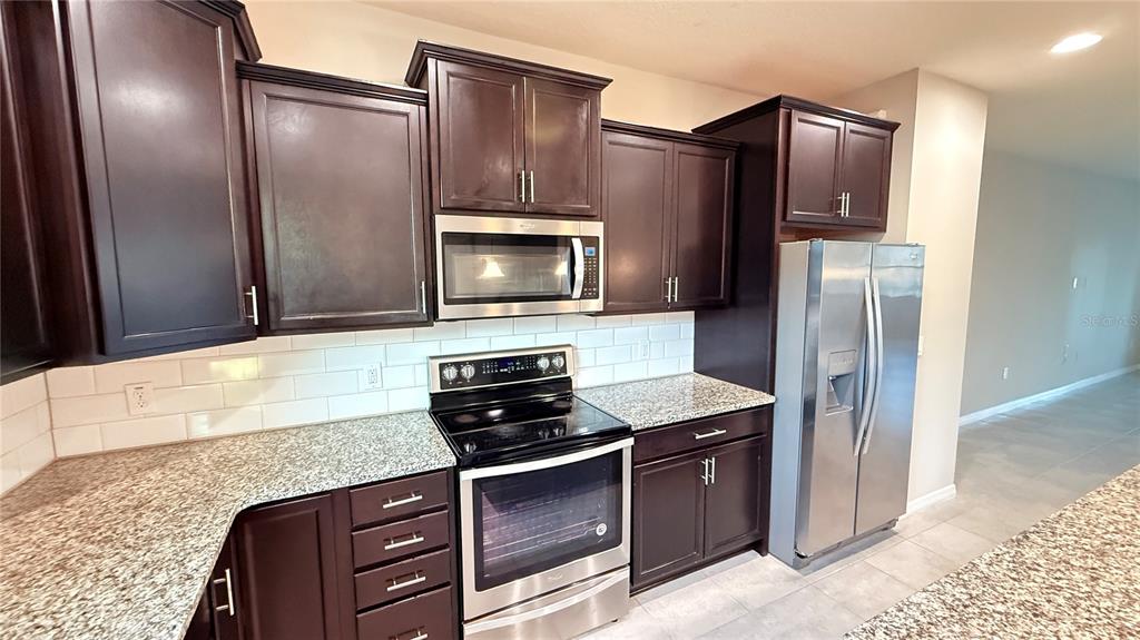 588 Piazza Point Oviedo, FL 32765 - Photo 16 of 66 a kitchen with granite countertop stainless steel appliances and wooden cabinets