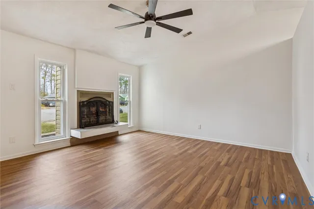 an empty room with wooden floor a fireplace and windows
