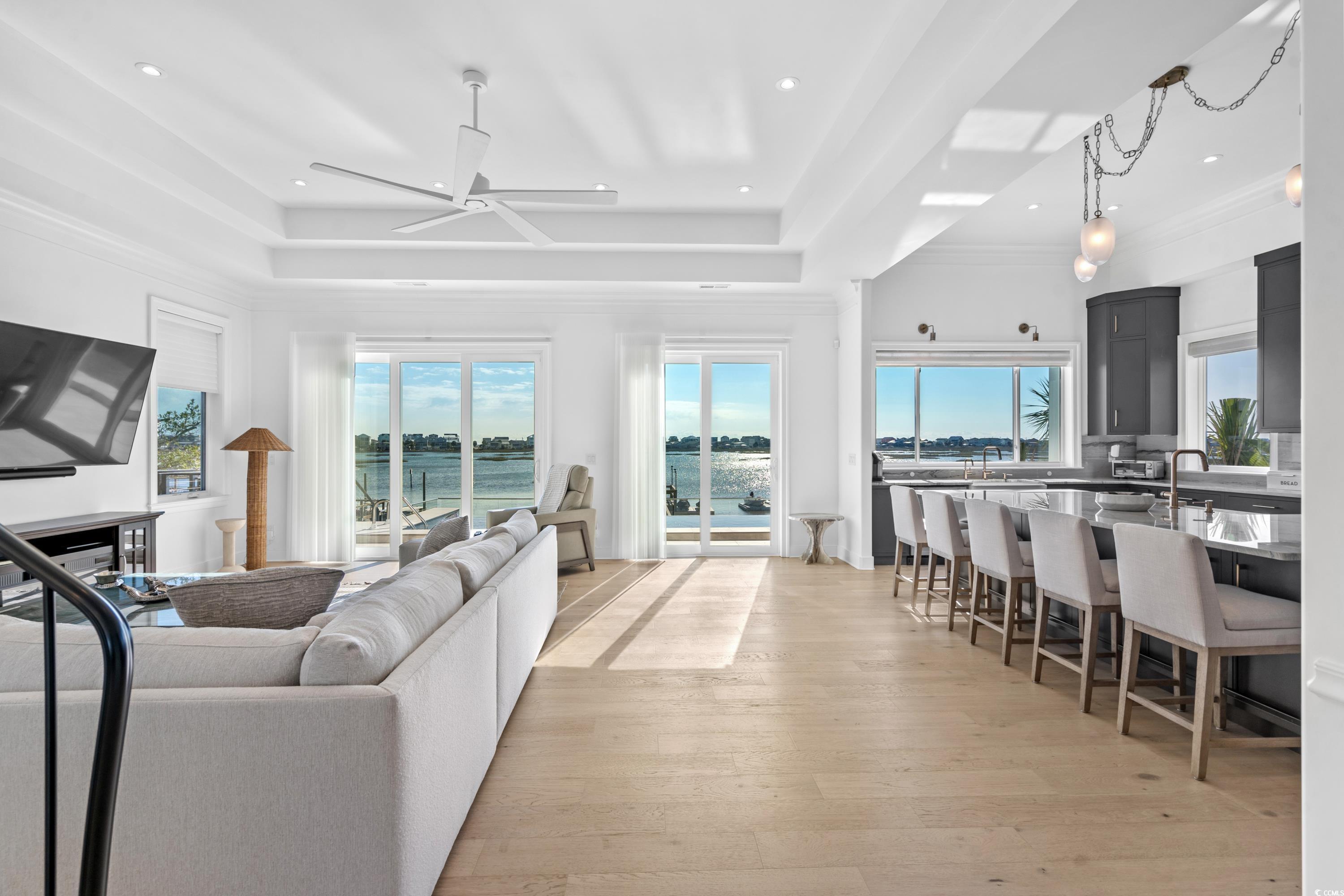 3109 State Rd S-26-816 Murrells Inlet, SC 29576 - Photo 15 of 40 Living room featuring light wood-type flooring, a raised ceiling, ceiling fan, and a healthy amount of sunlight