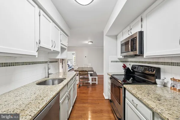 a kitchen with kitchen island granite countertop a sink stove and cabinets