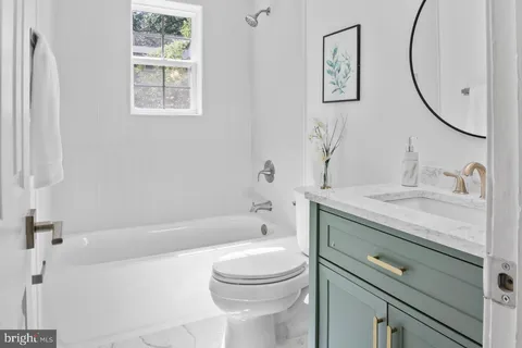 a bathroom with a granite countertop toilet a sink and a bathtub