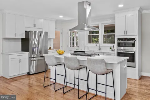 a kitchen with stainless steel appliances granite countertop a stove top oven a refrigerator a sink and a dining table with wooden floor