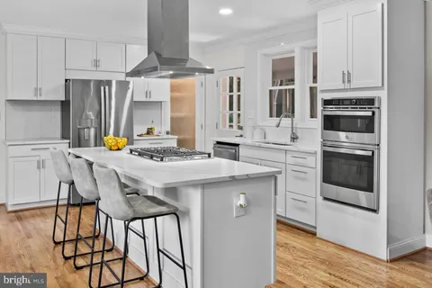 a kitchen with stainless steel appliances kitchen island granite countertop a table chairs sink and cabinets