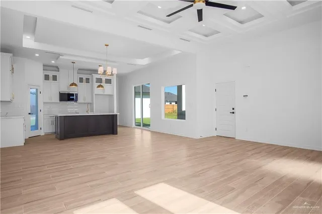 a view of a big room with wooden floor and a kitchen