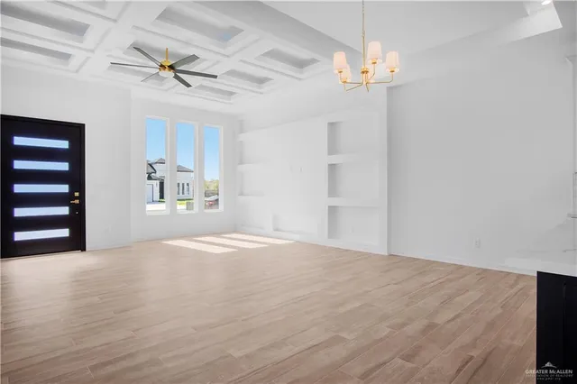a view of a livingroom with a chandelier fan and wooden floor