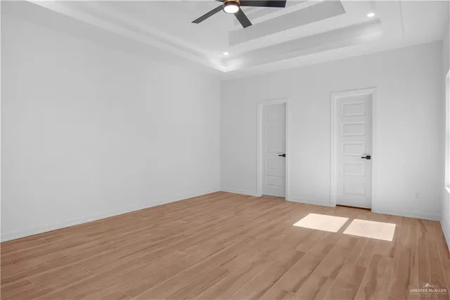 an empty room with wooden floor ceiling fan and windows