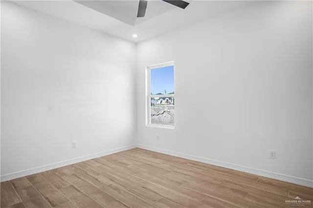 an empty room with wooden floor and ceiling fan
